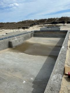 A concrete pool is being built on the beach.