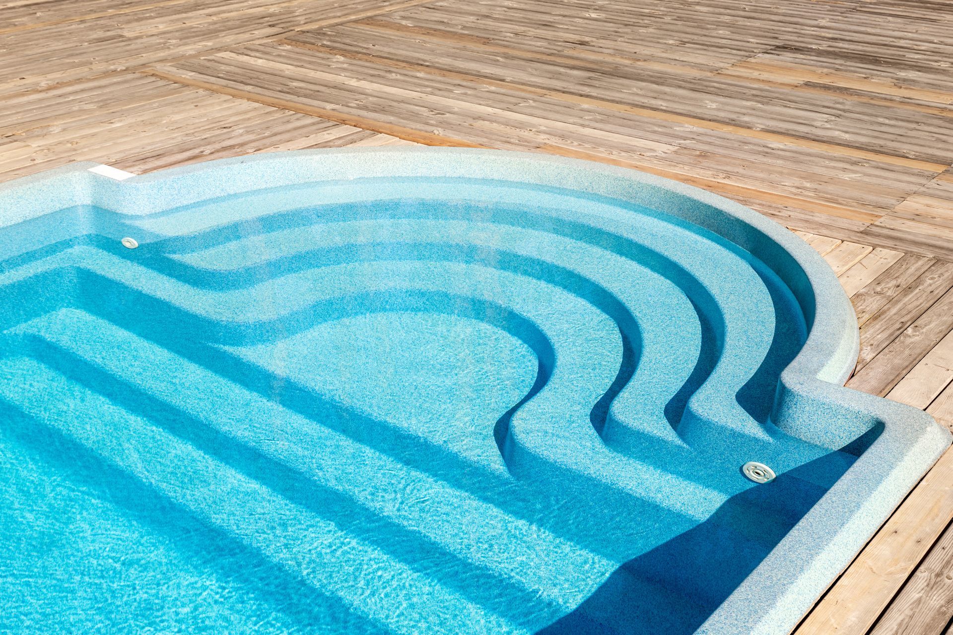 A swimming pool with stairs leading up to it on a wooden deck.