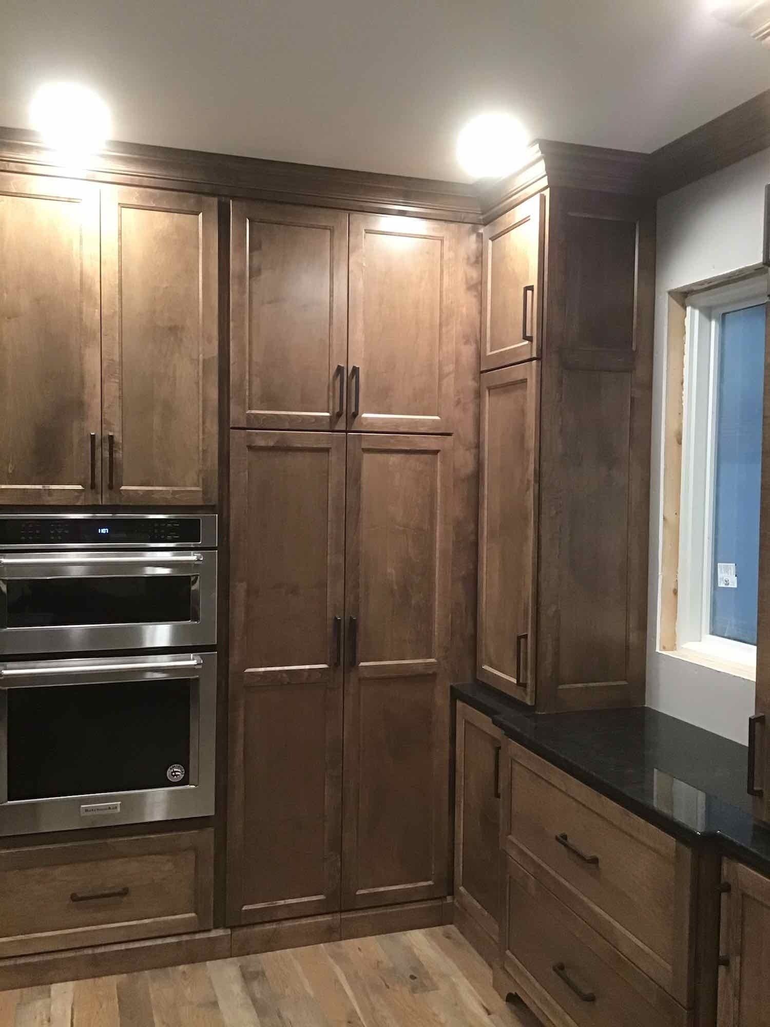 A kitchen with wooden cabinets , stainless steel appliances , and a window.