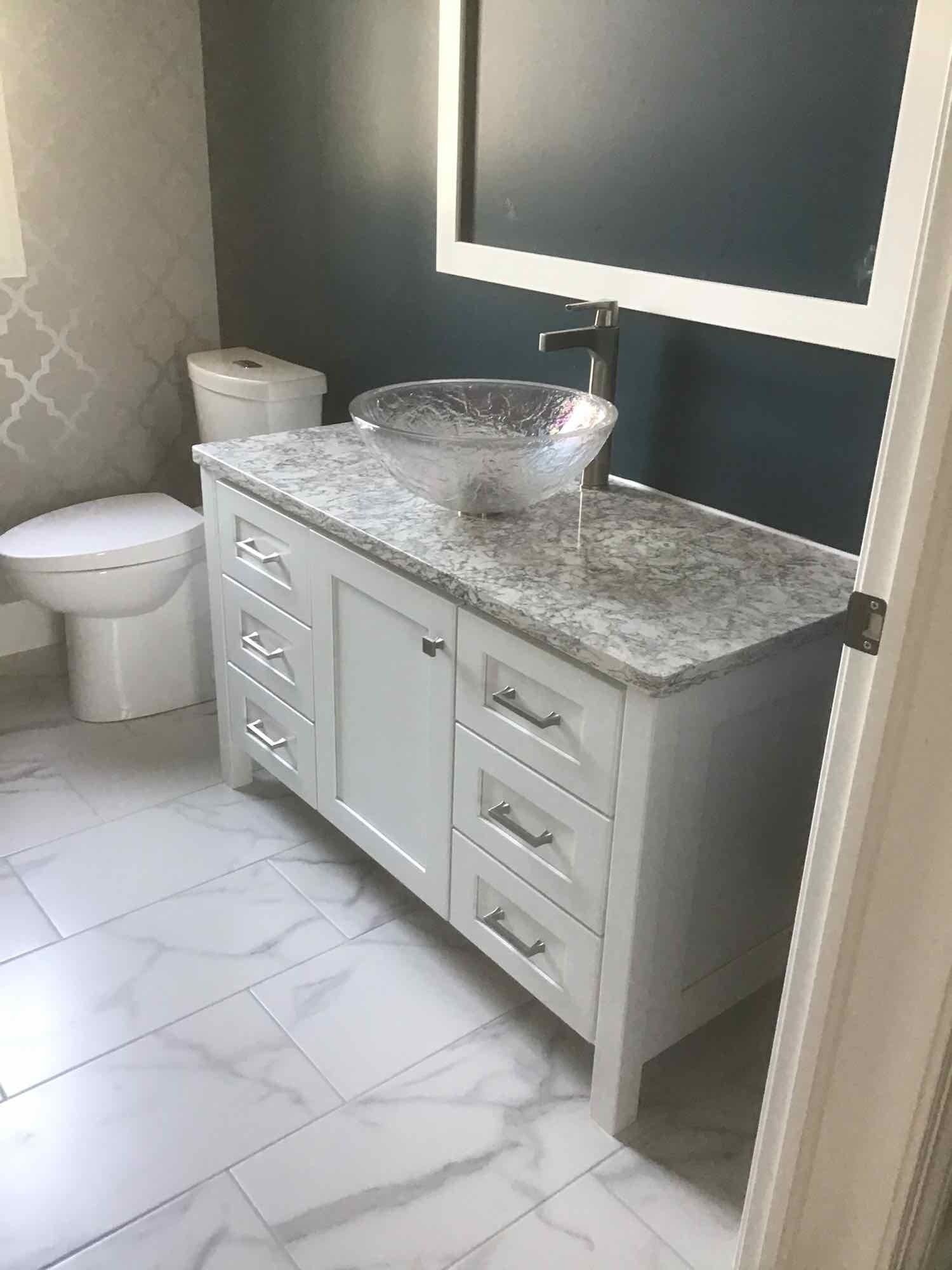 A bathroom with a glass sink , toilet, and mirror.