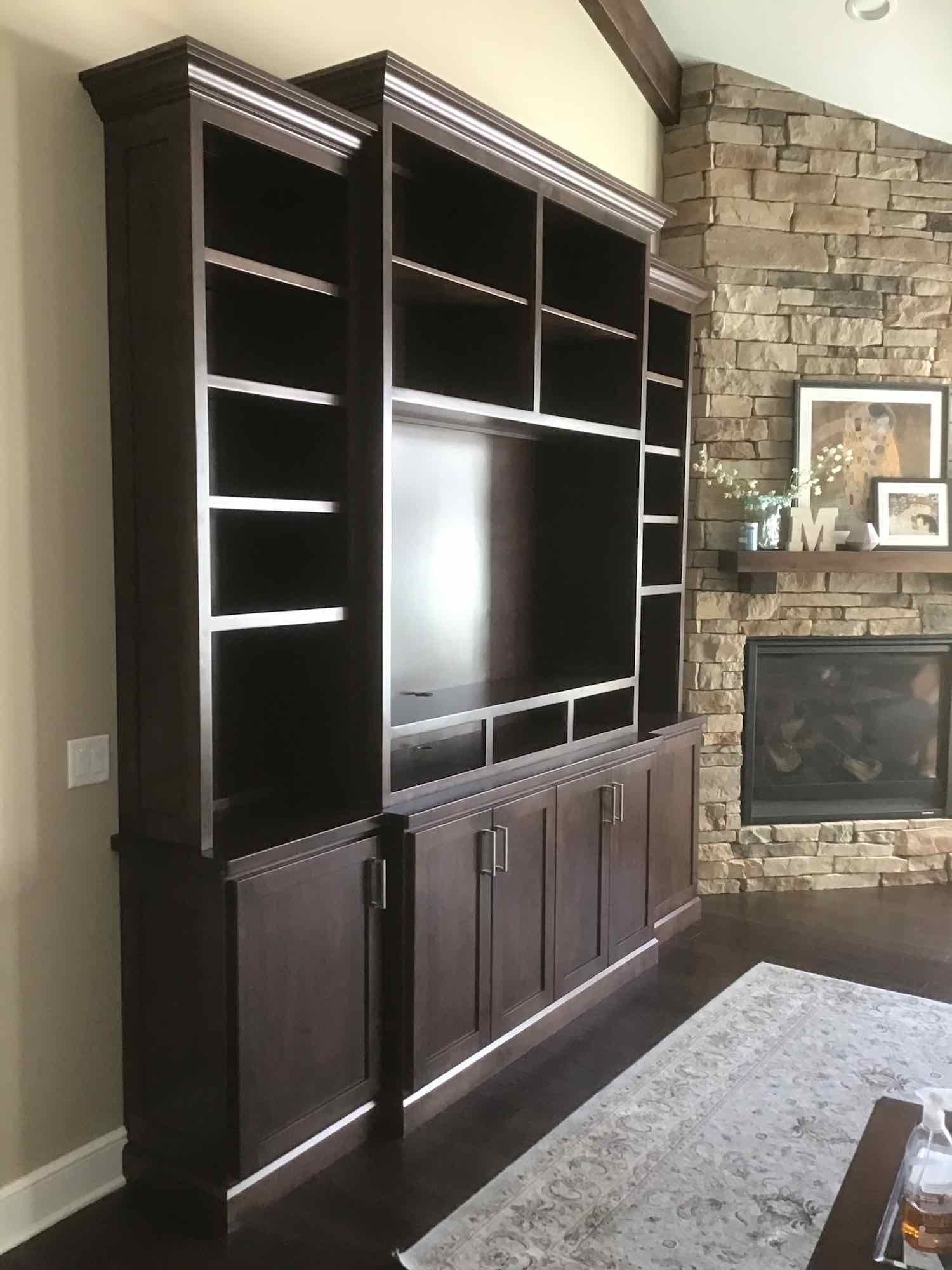 A living room with a large entertainment center, built-in shelf, and a fireplace.