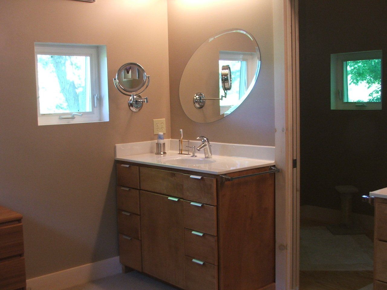 A bathroom with a sink a mirror and a window.