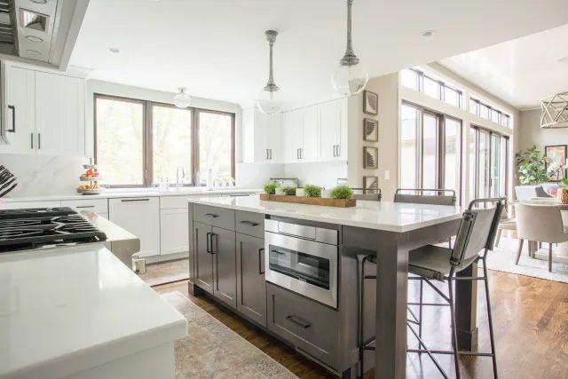 A kitchen with white cabinets, stainless steel appliances, and a large island.