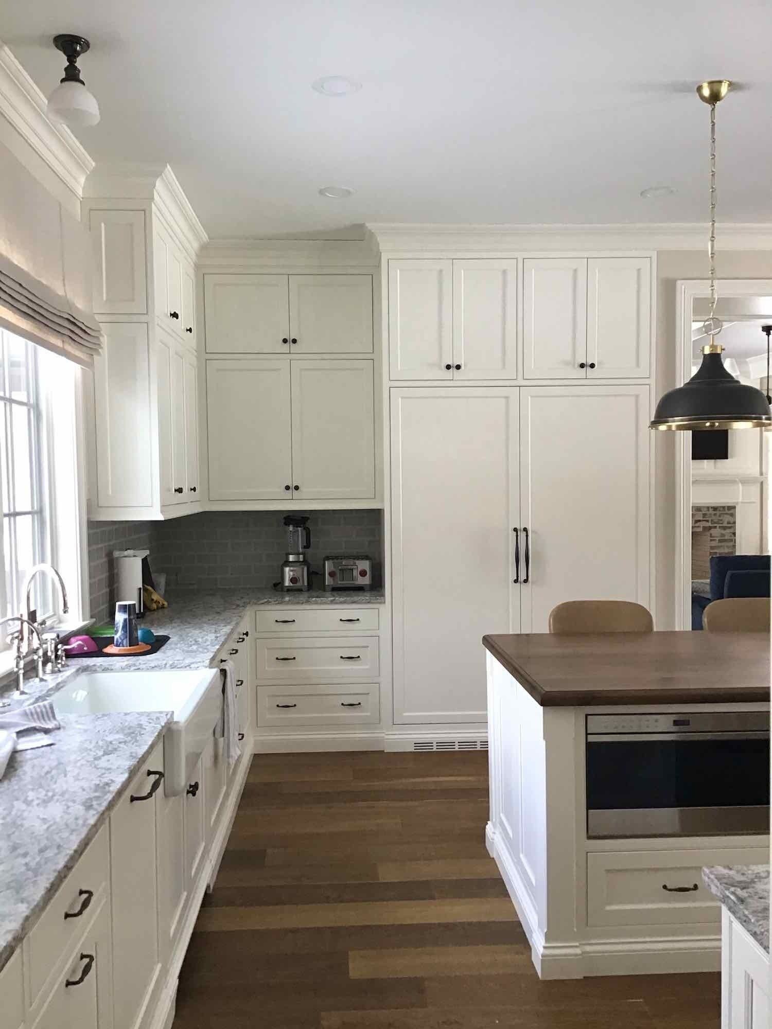 A kitchen with white cabinets , granite counter tops , and a large island.