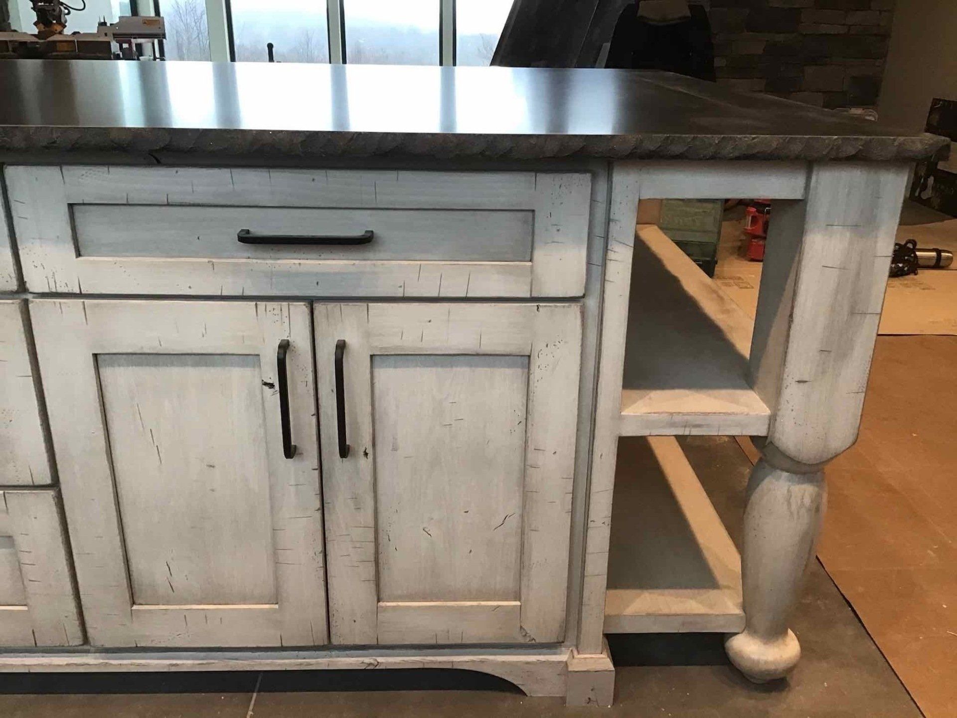 A kitchen island with white cabinets and a stainless steel counter top