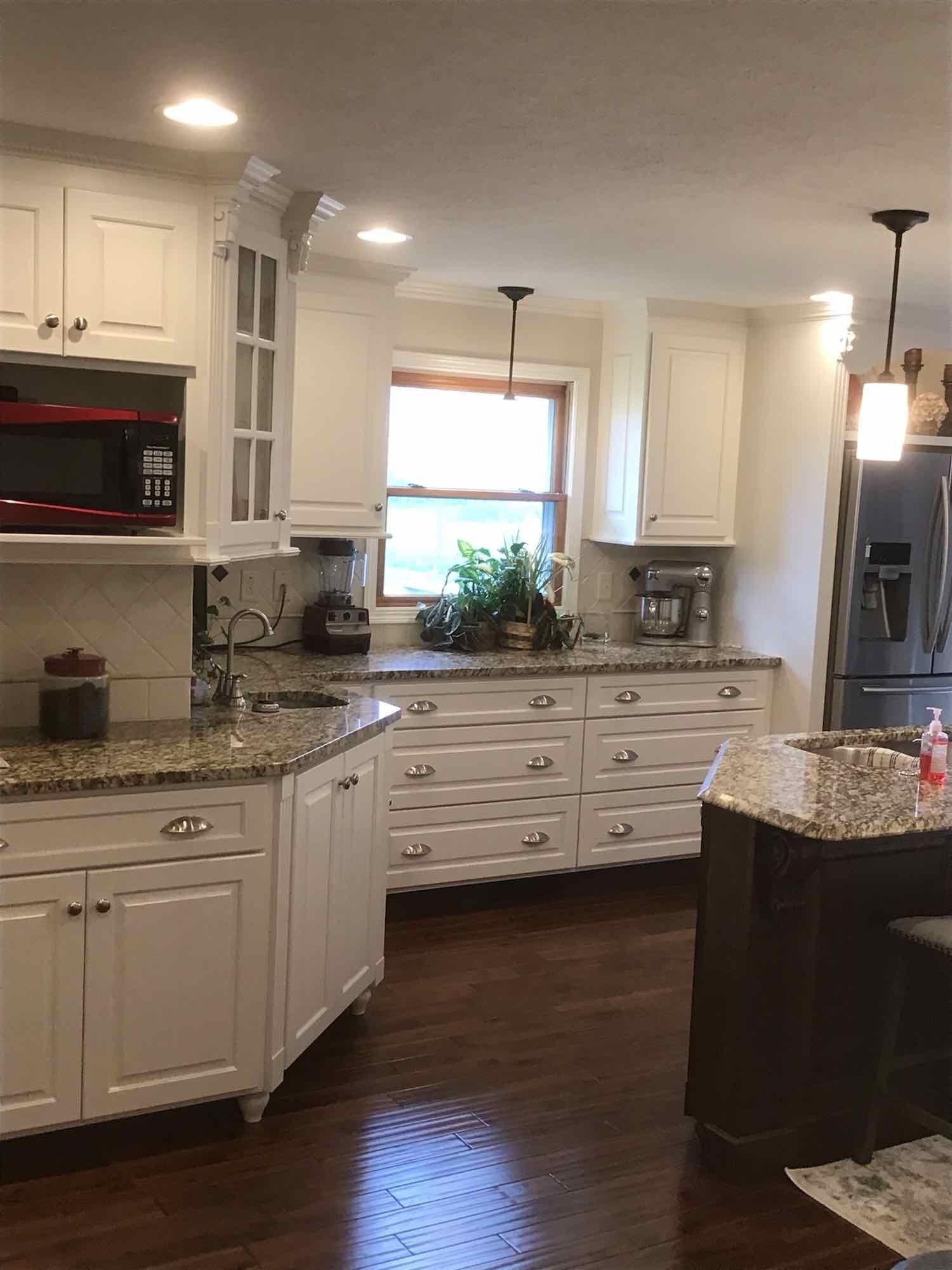 A kitchen with white cabinets and granite counter tops.