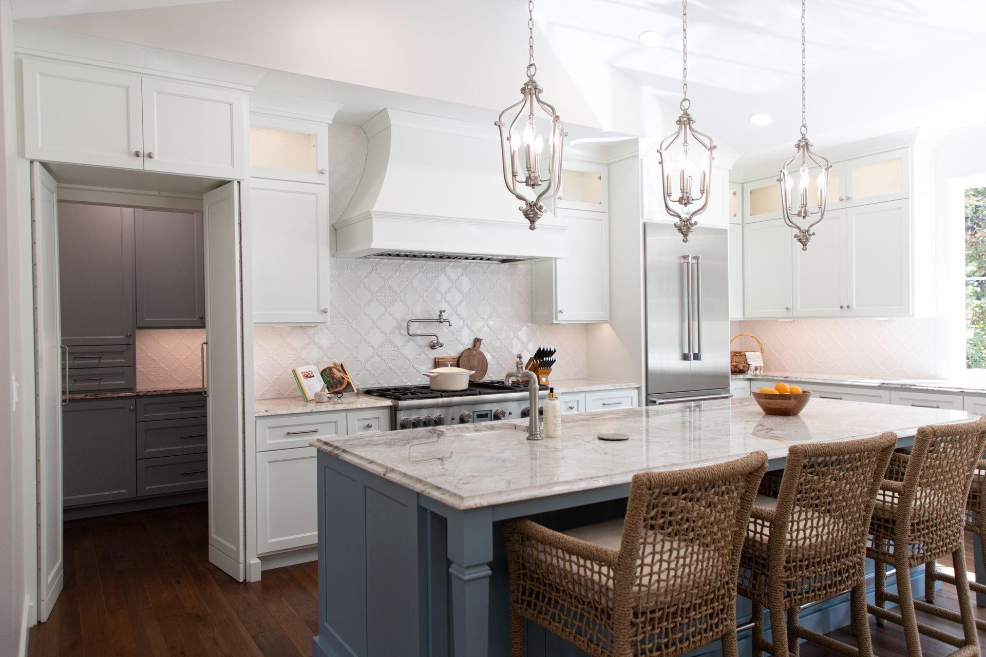 A kitchen with a large island and wicker chairs.