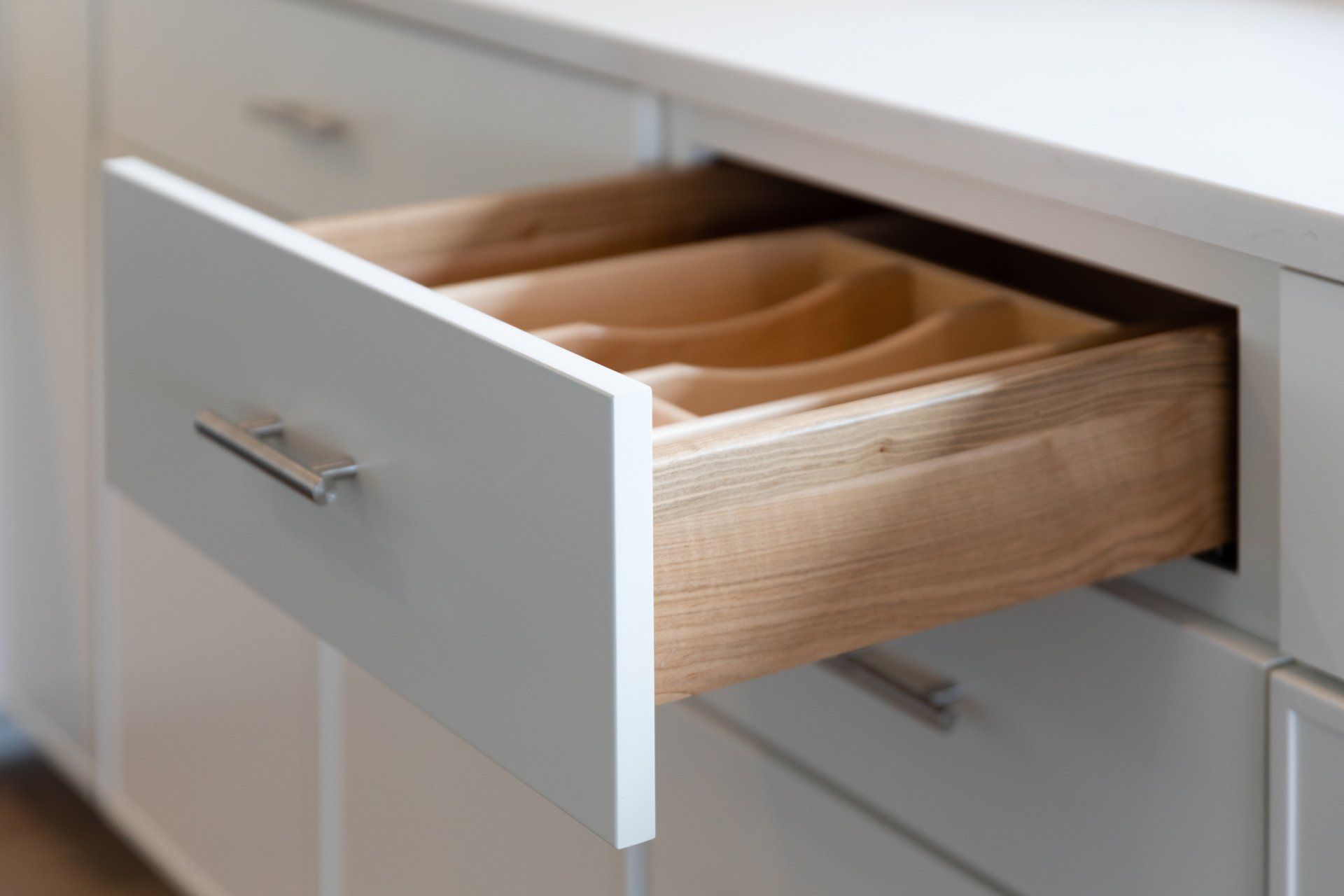 A kitchen drawer with a wooden utensil tray in it.