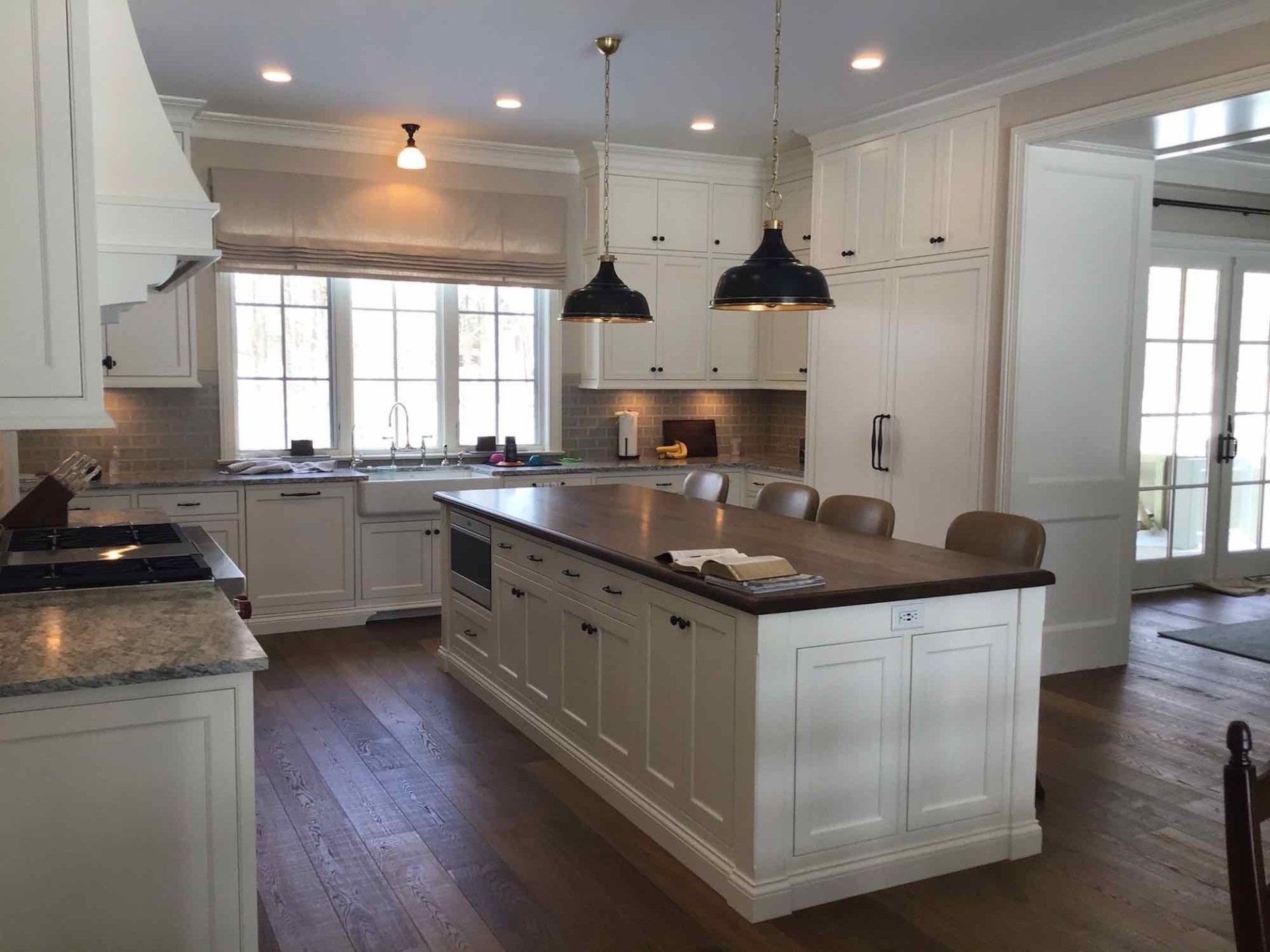 A kitchen with white cabinets and a large island in the middle.