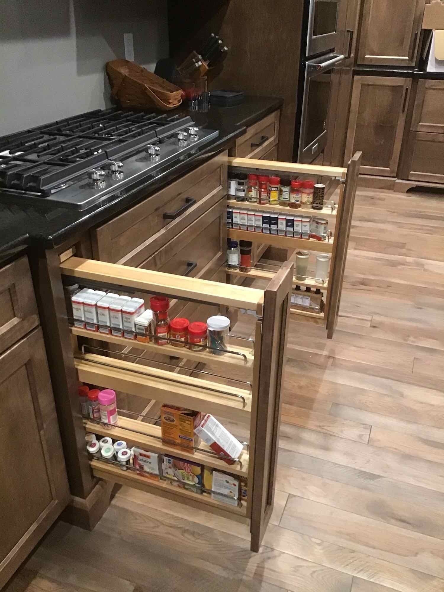 A kitchen with wooden cabinets and drawers filled with spices.