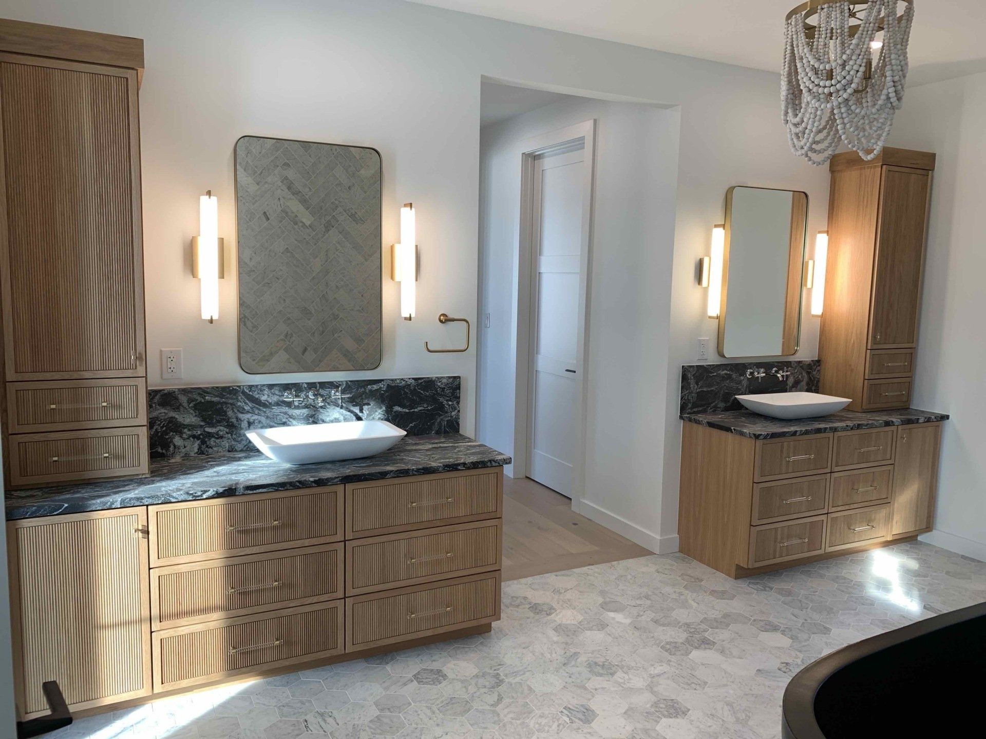 A bathroom with two sinks, two mirrors, and a chandelier.