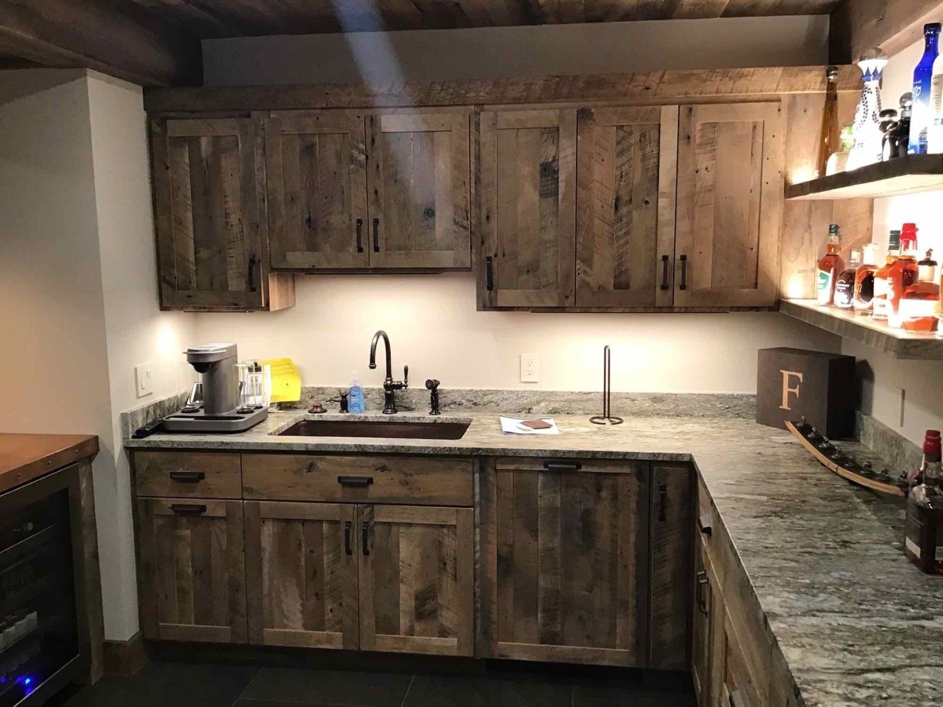 A kitchen with custom wooden cabinets, granite counter tops, and a sink.