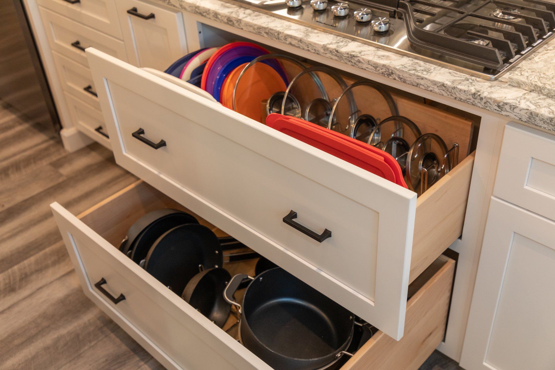 A kitchen drawer filled with pots,  pans, and plates.