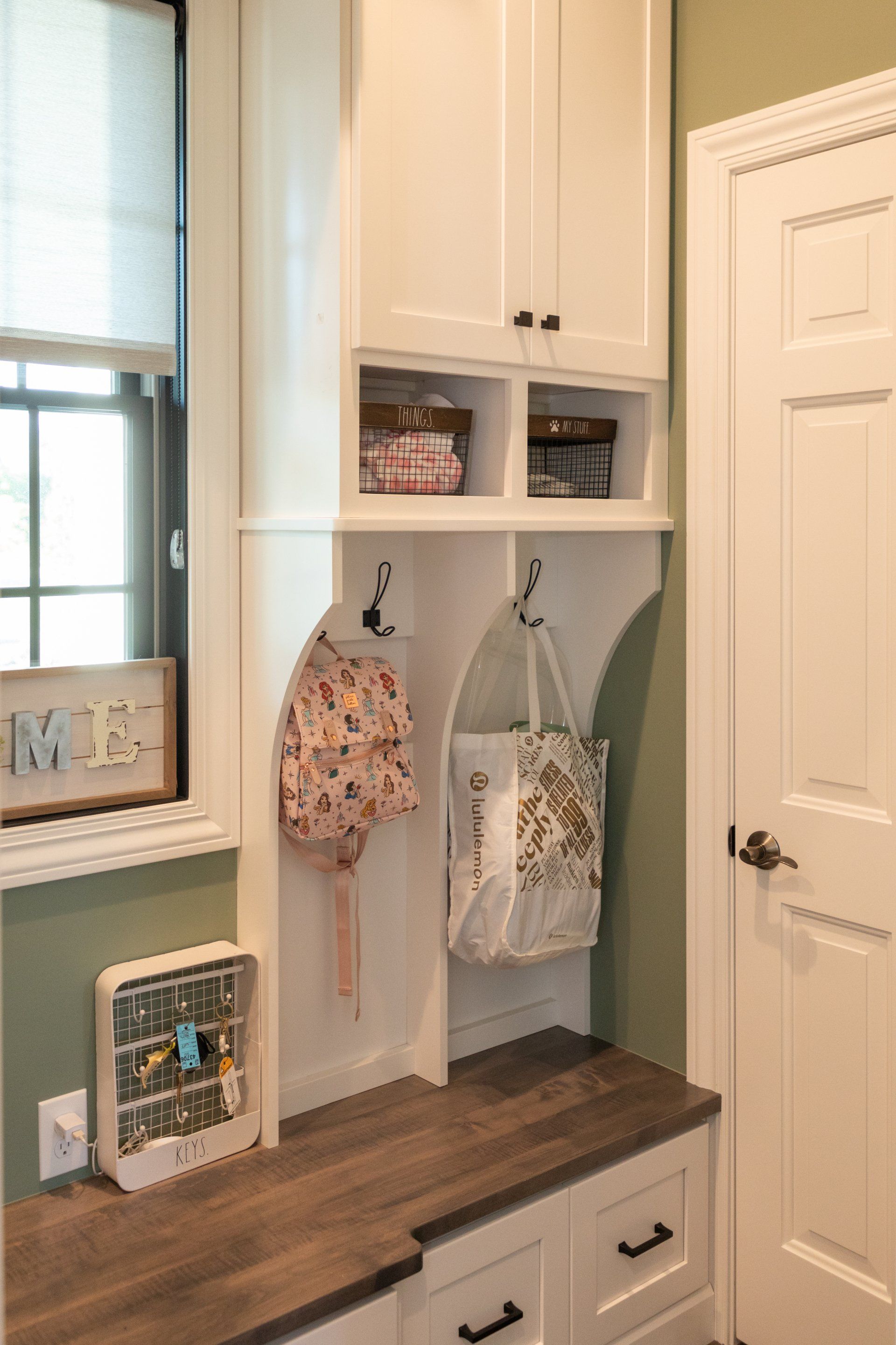 A hallway with white cabinets , drawers , and a mirror.