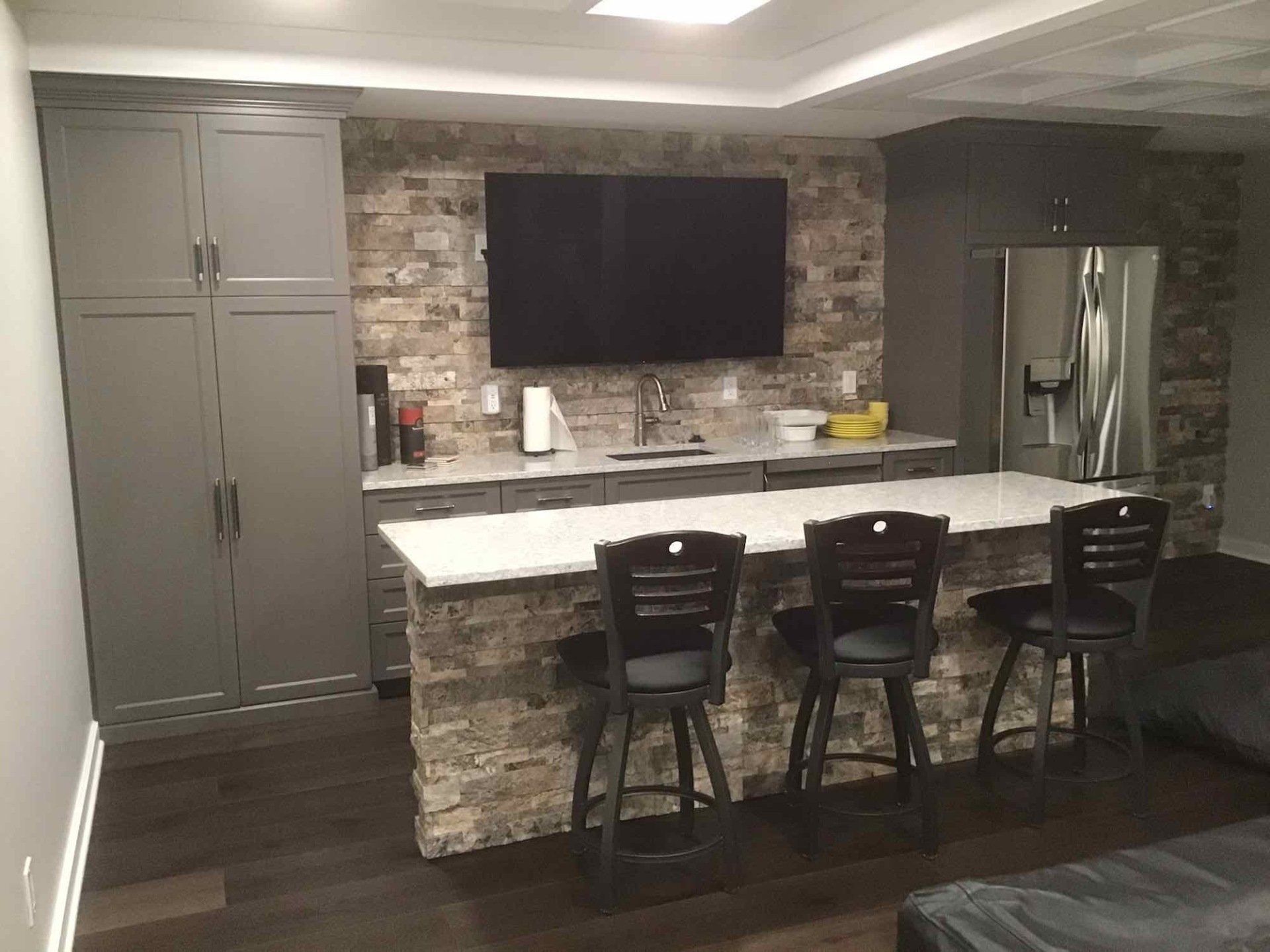 A kitchen with a bar and a flat screen tv on the wall.