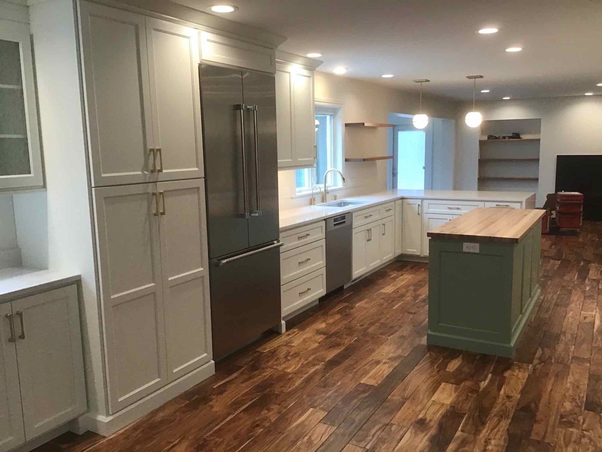 A kitchen with white cabinets , stainless steel appliances , and wooden floors.
