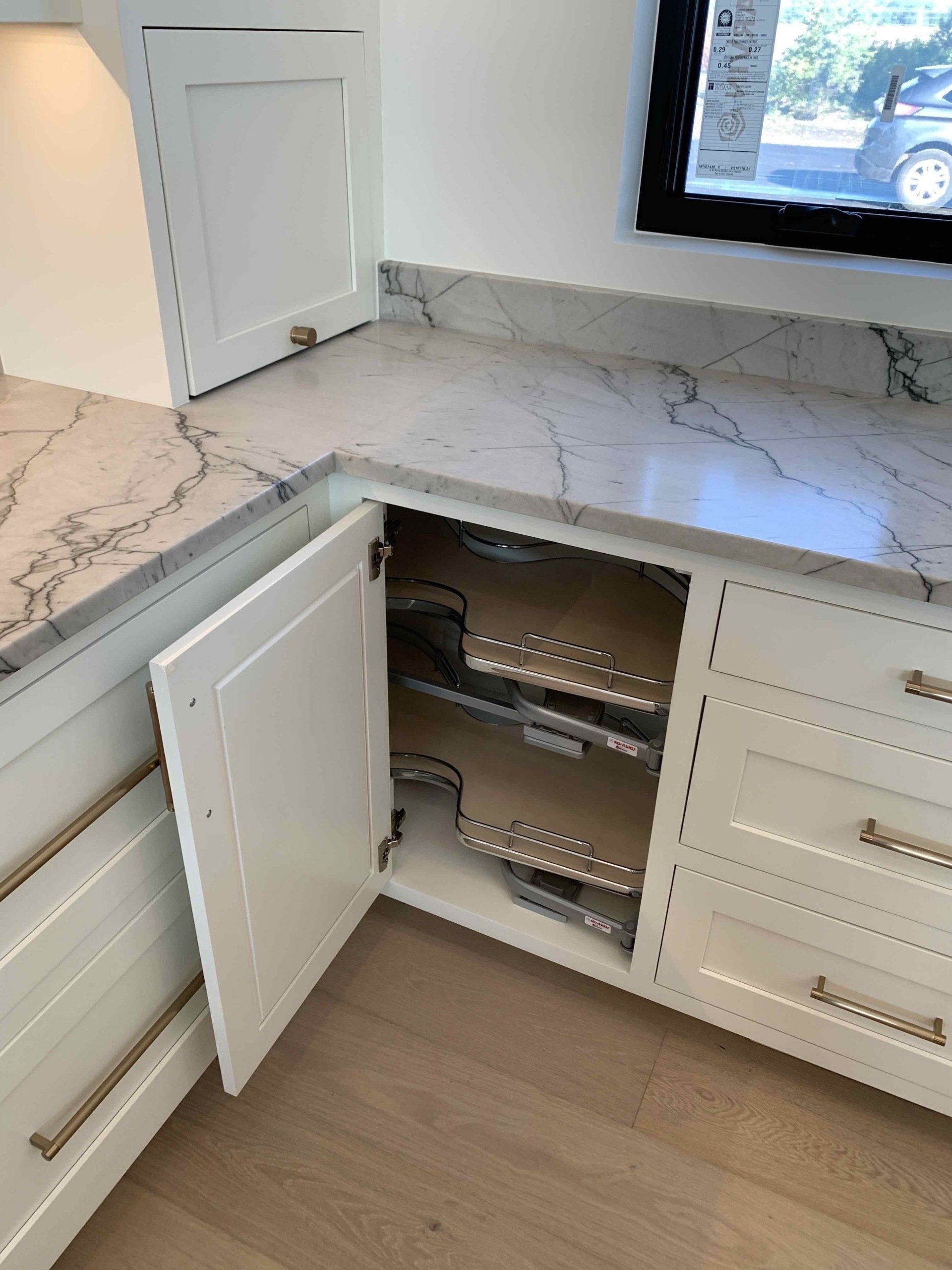 A kitchen with white cabinets and a marble counter top.