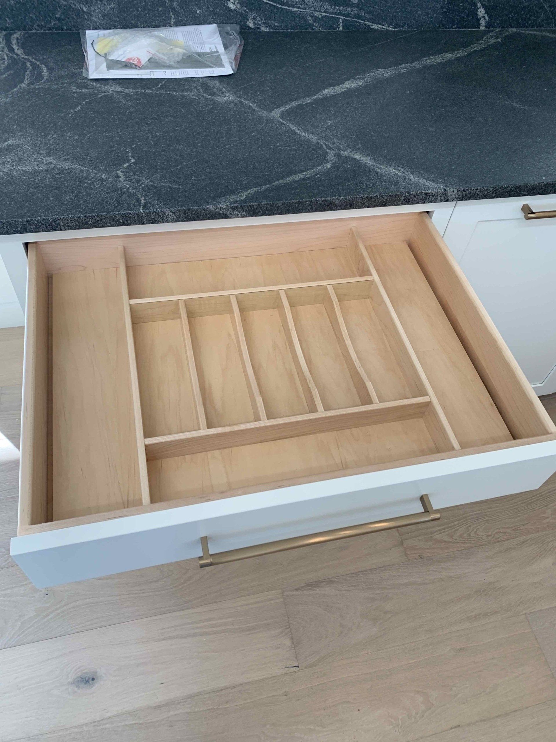 A kitchen drawer with a wooden cutlery tray in it.