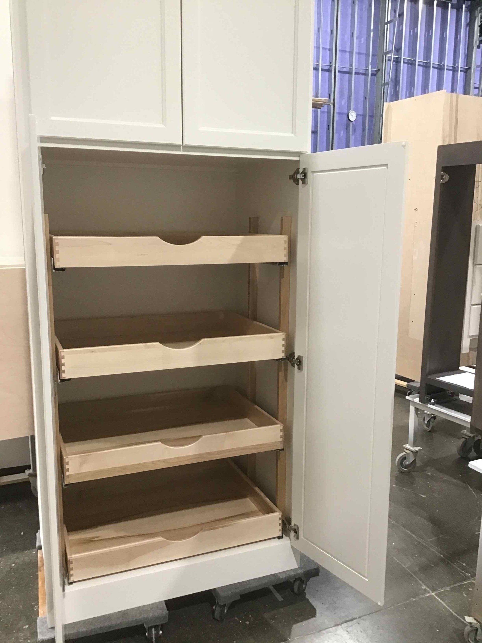 A white cabinet with wooden shelves and drawers is being built.
