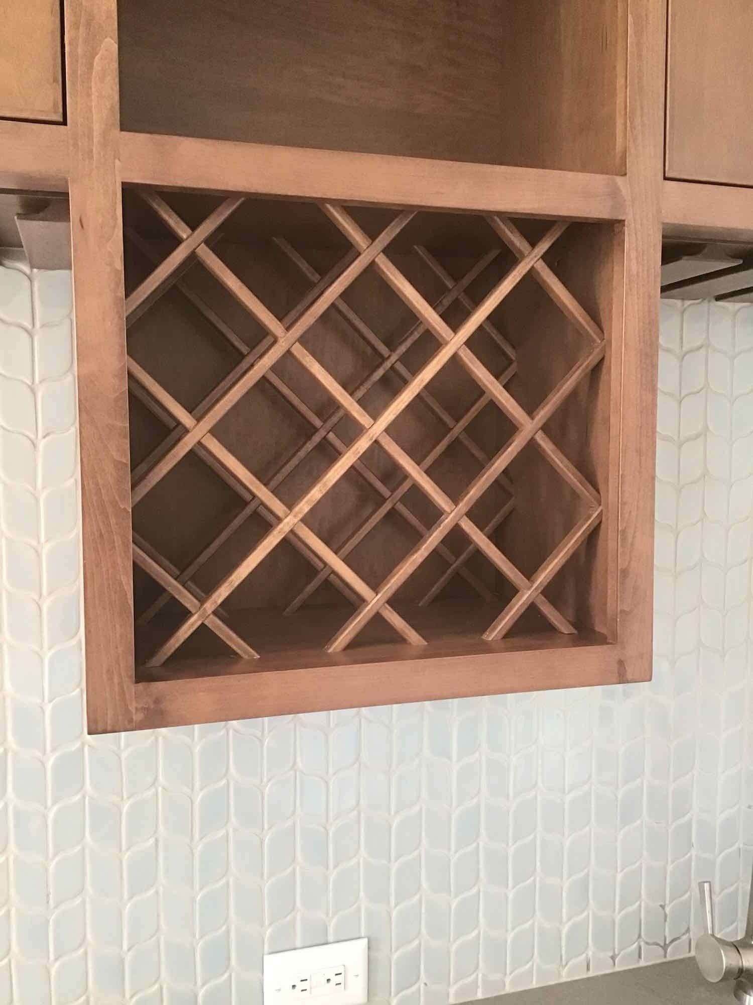 A wooden wine rack is hanging from the ceiling in a kitchen.