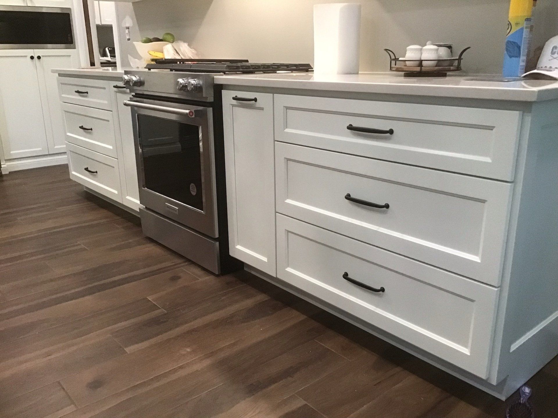 A kitchen with white cabinets , a stove , and a sink.