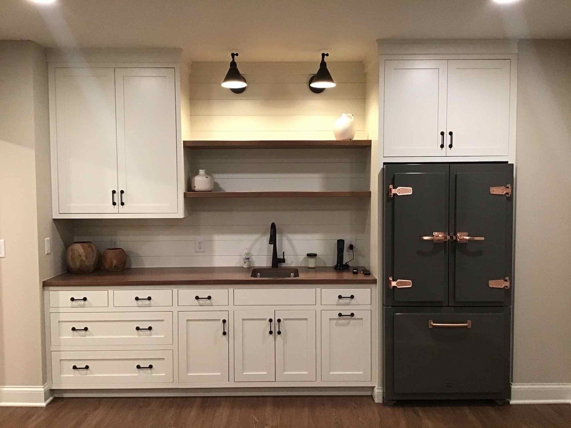A kitchen with white cabinets and a black refrigerator.