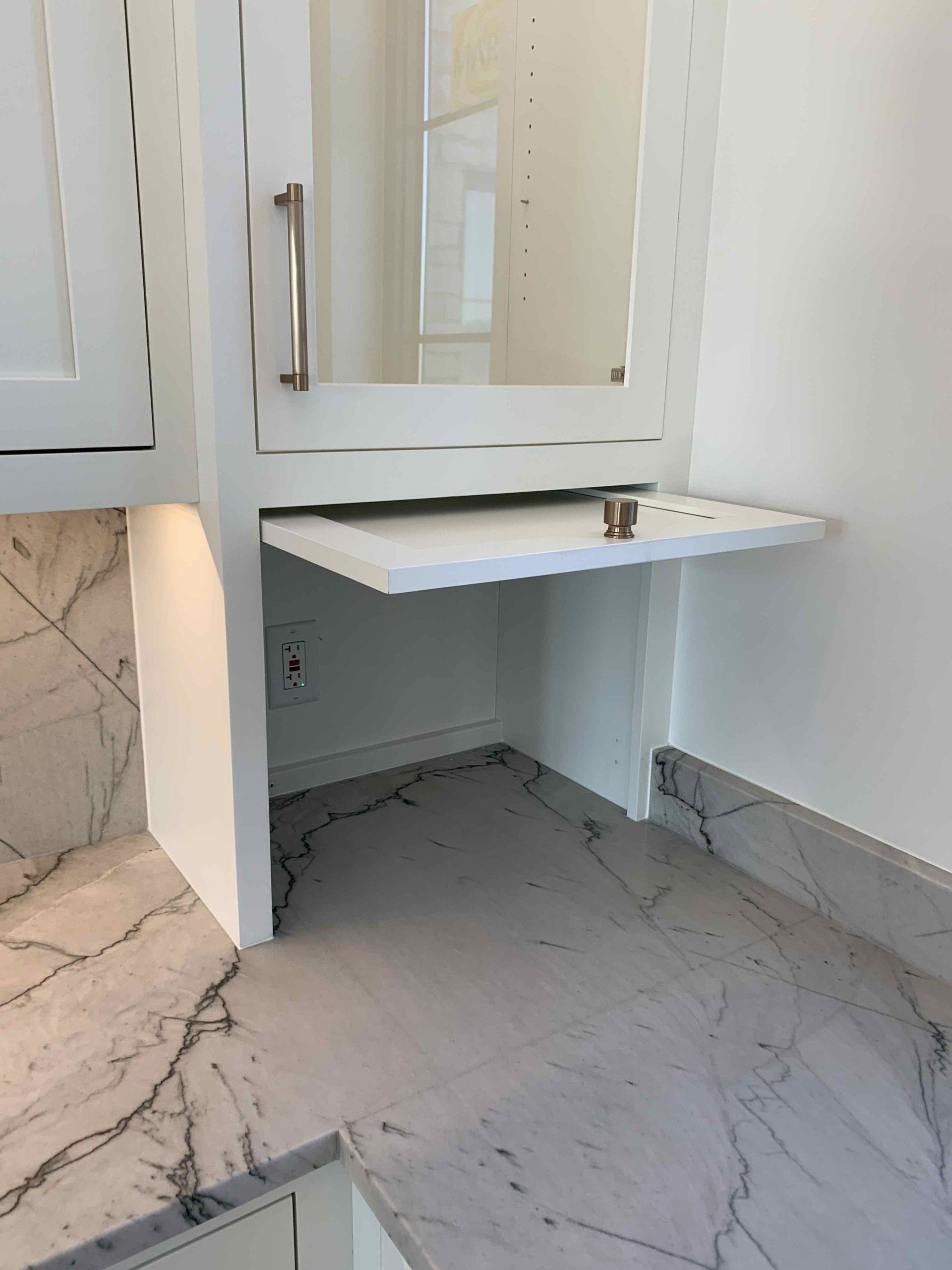 A kitchen with white cabinets and a marble counter top.