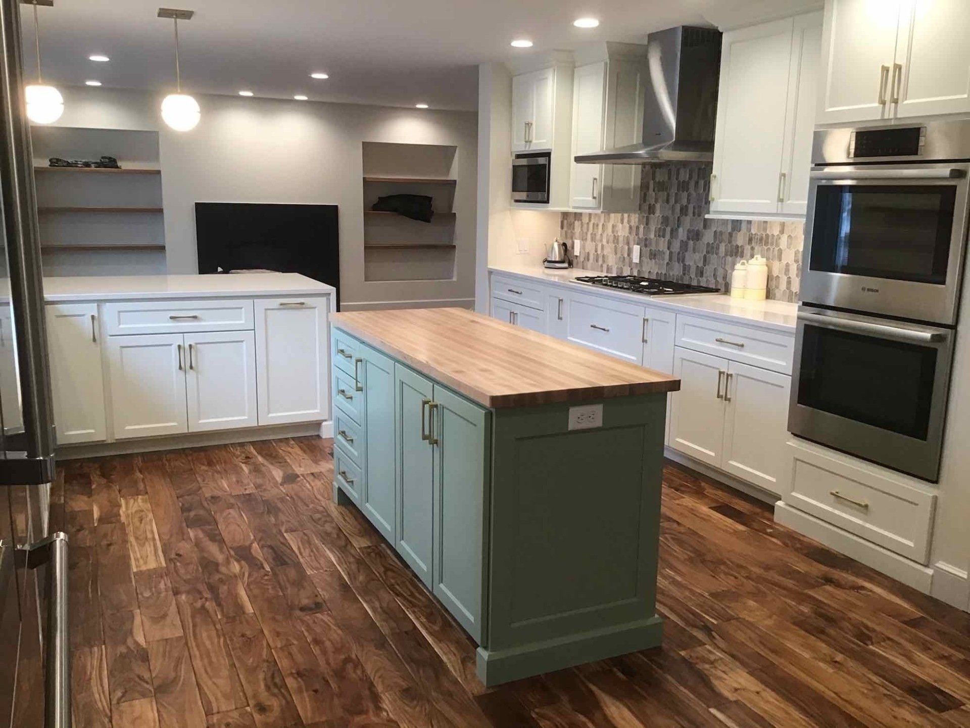 A kitchen with a large island in the middle and stainless steel appliances.