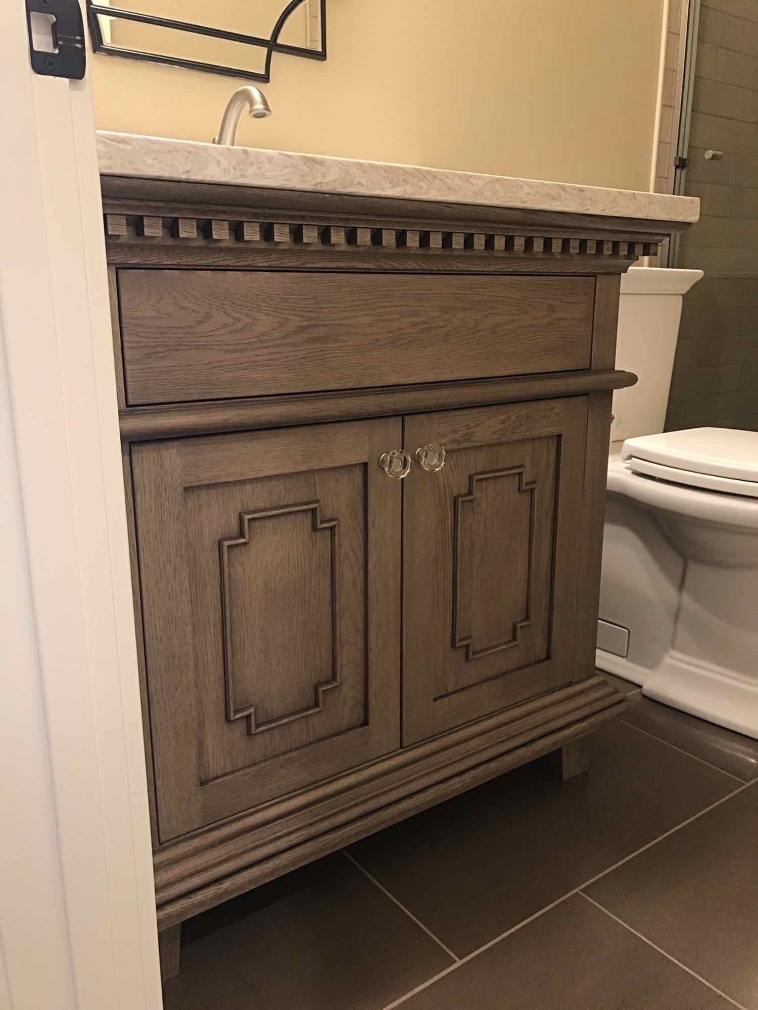 A bathroom with a sink , toilet, mirror, and custom cabinetry.