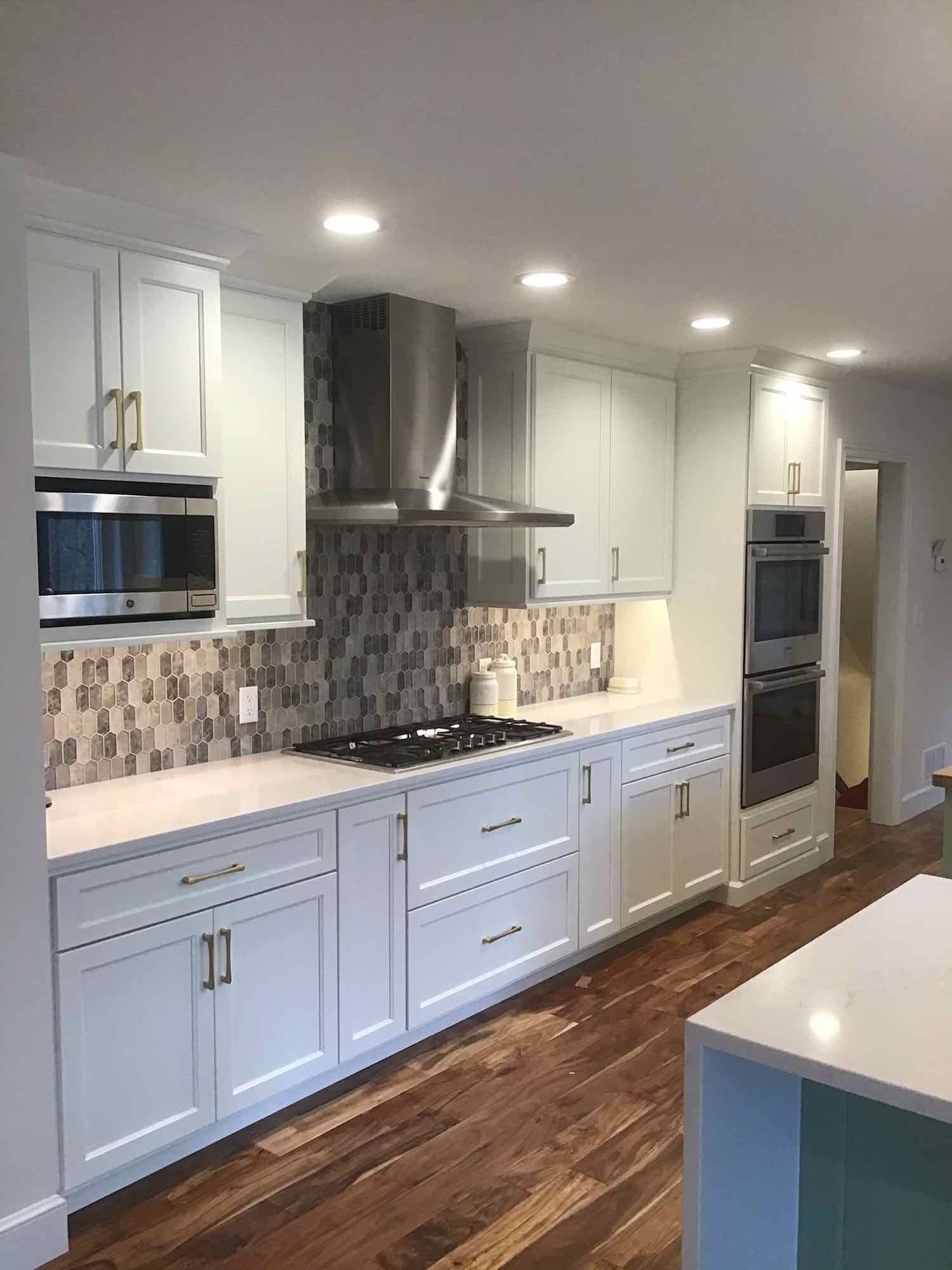 A kitchen with white cabinets , stainless steel appliances , and wooden floors.