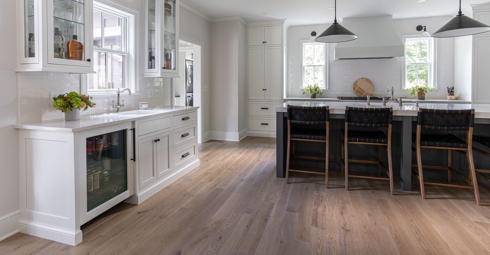 A kitchen with hardwood floors , white cabinets , and a large island.