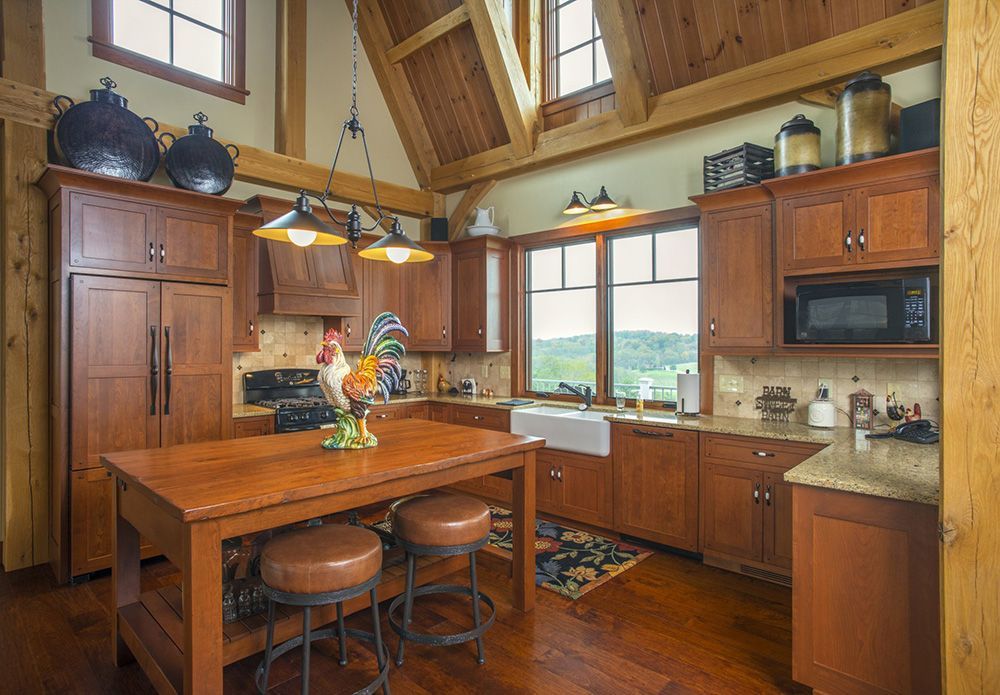 A kitchen with wooden cabinets , granite counter tops , a table and stools.