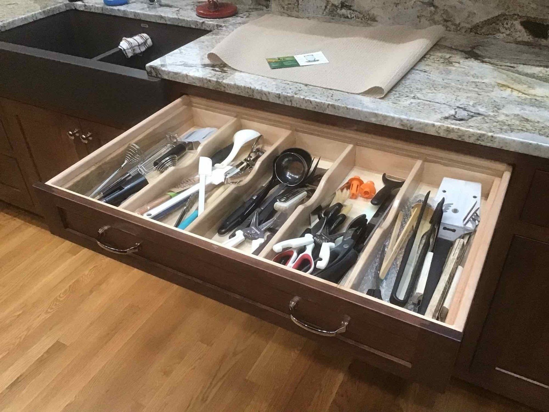 A kitchen drawer filled with utensils and a sink.