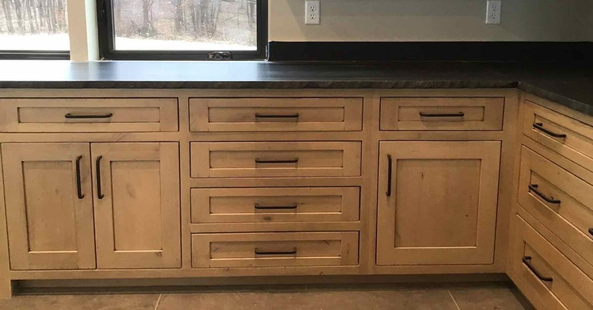 A kitchen with wooden cabinets and drawers and a black counter top.