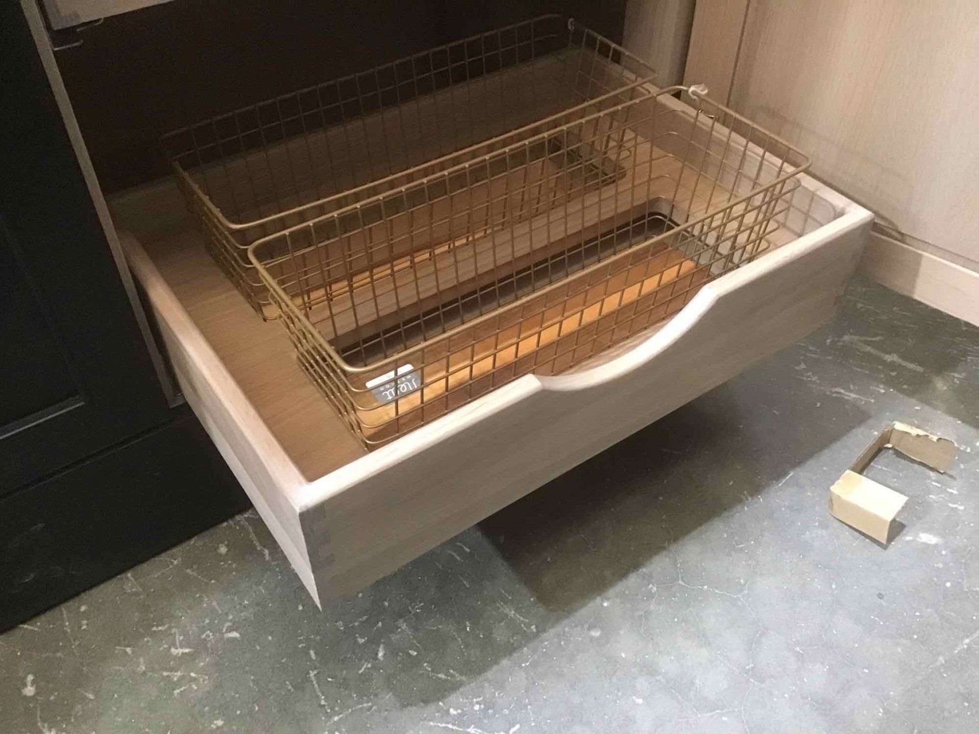 A kitchen drawer with a wire basket in it.