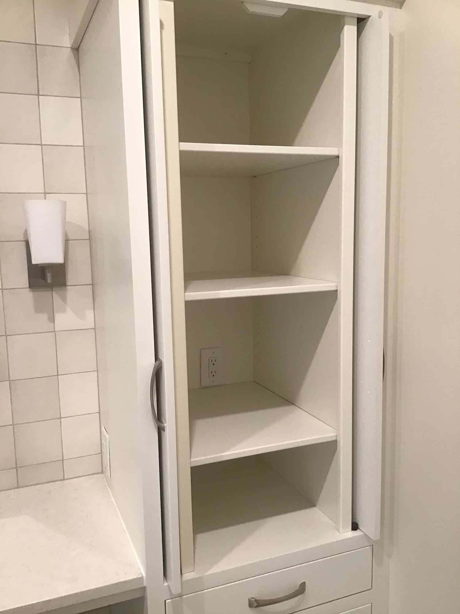 A white cabinet with shelves and a drawer in a kitchen.