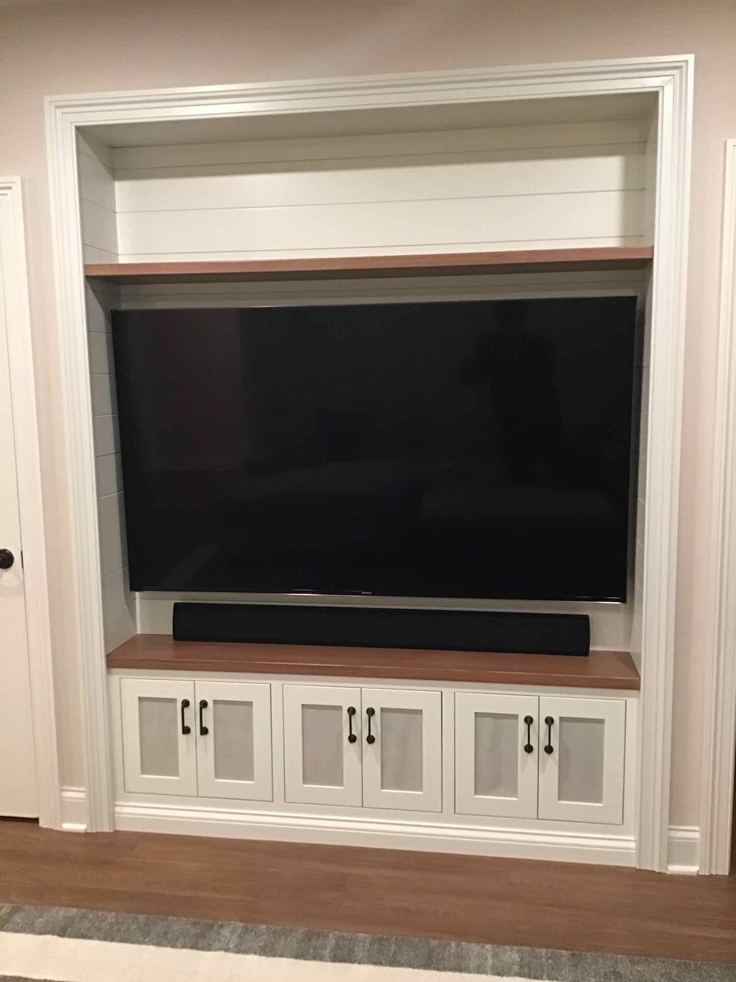 A large flat screen tv is sitting on top of a custom wooden entertainment center.