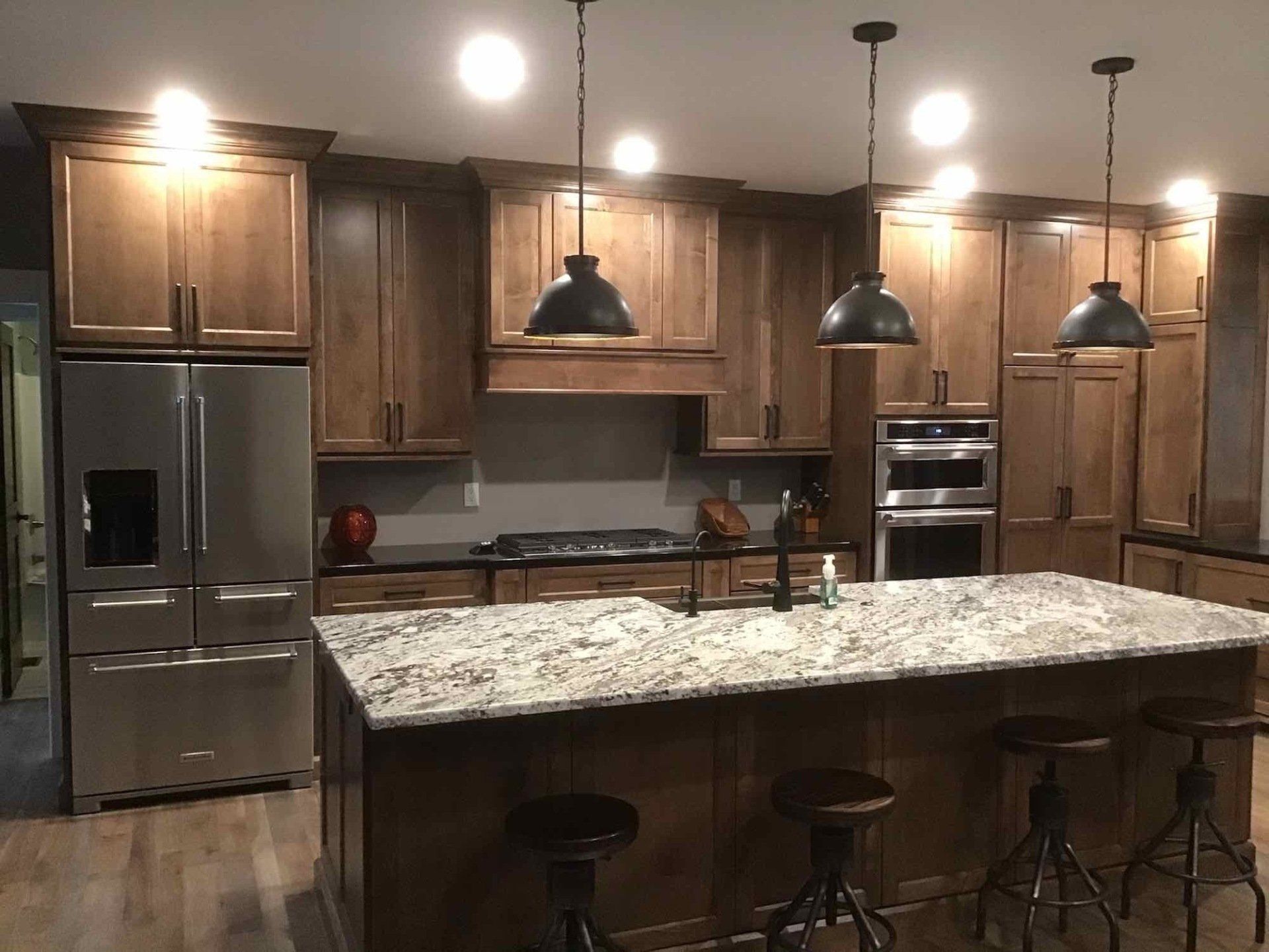 A kitchen with an island, stainless steel appliances, and granite counter tops.