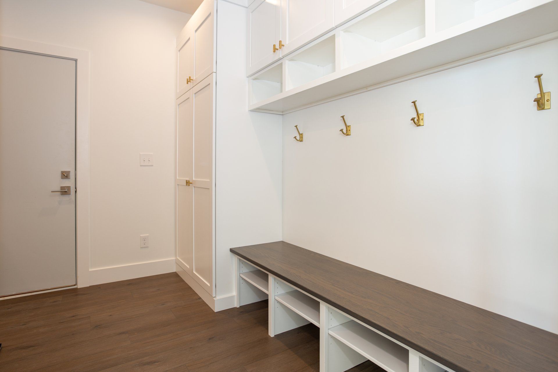 A hallway with a bench and hooks on the wall.