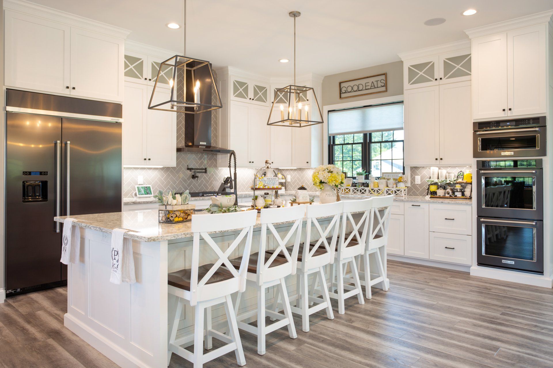 A kitchen with white cabinets, stainless steel appliances, and a large island.