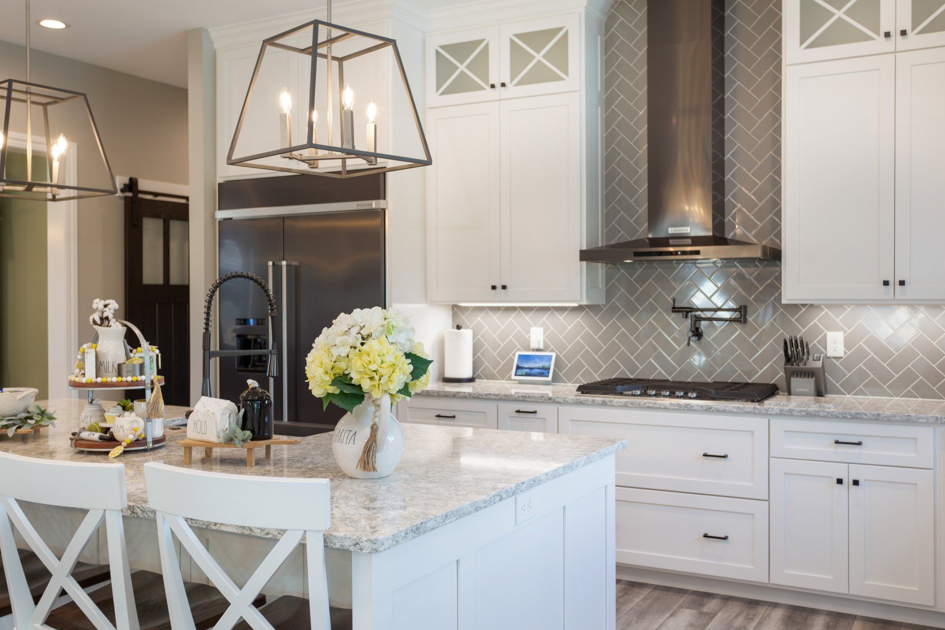 A kitchen with white cabinets , granite counter tops , stainless steel appliances, and a large island.