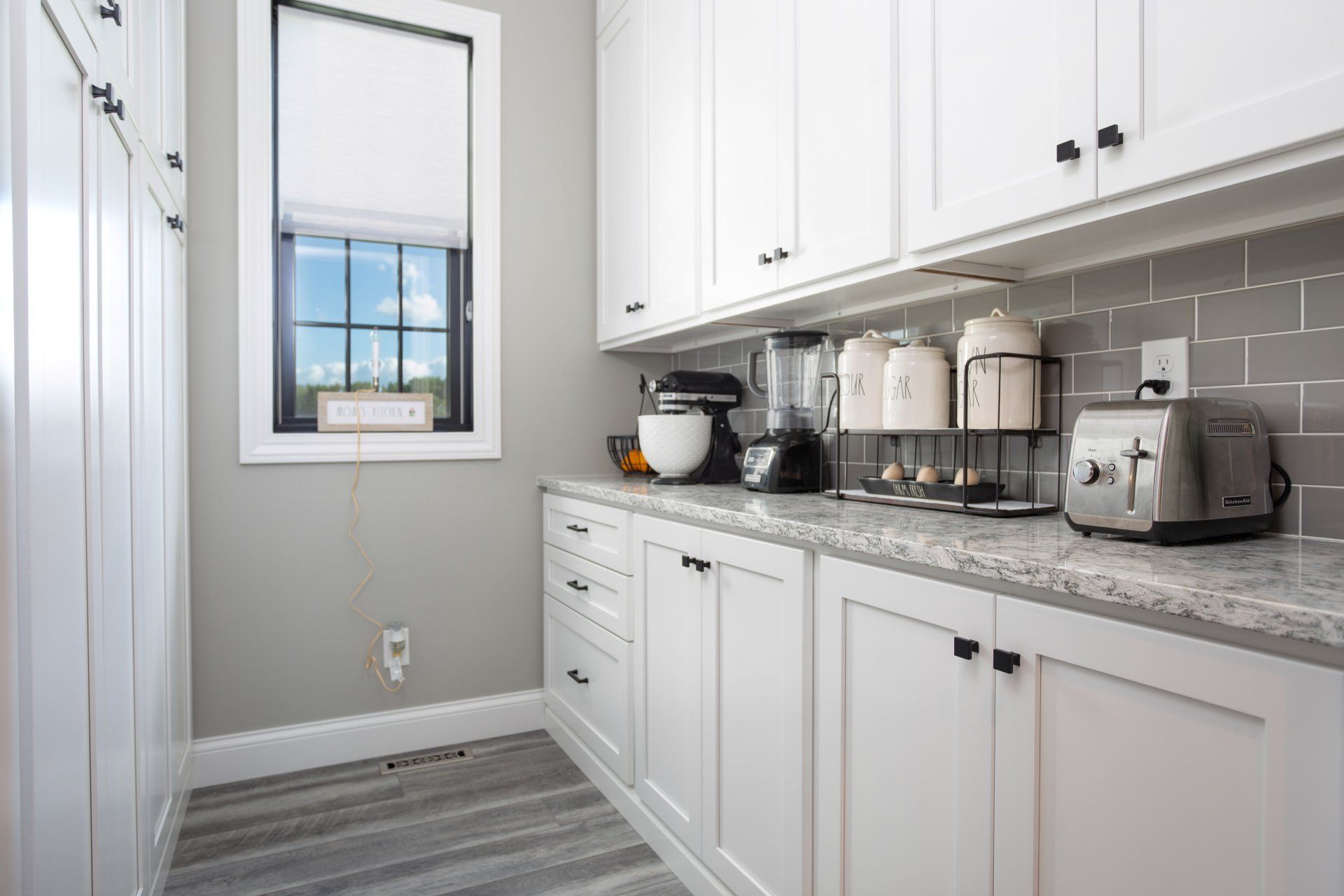 A kitchen with white cabinet, granite counter tops, and a window.