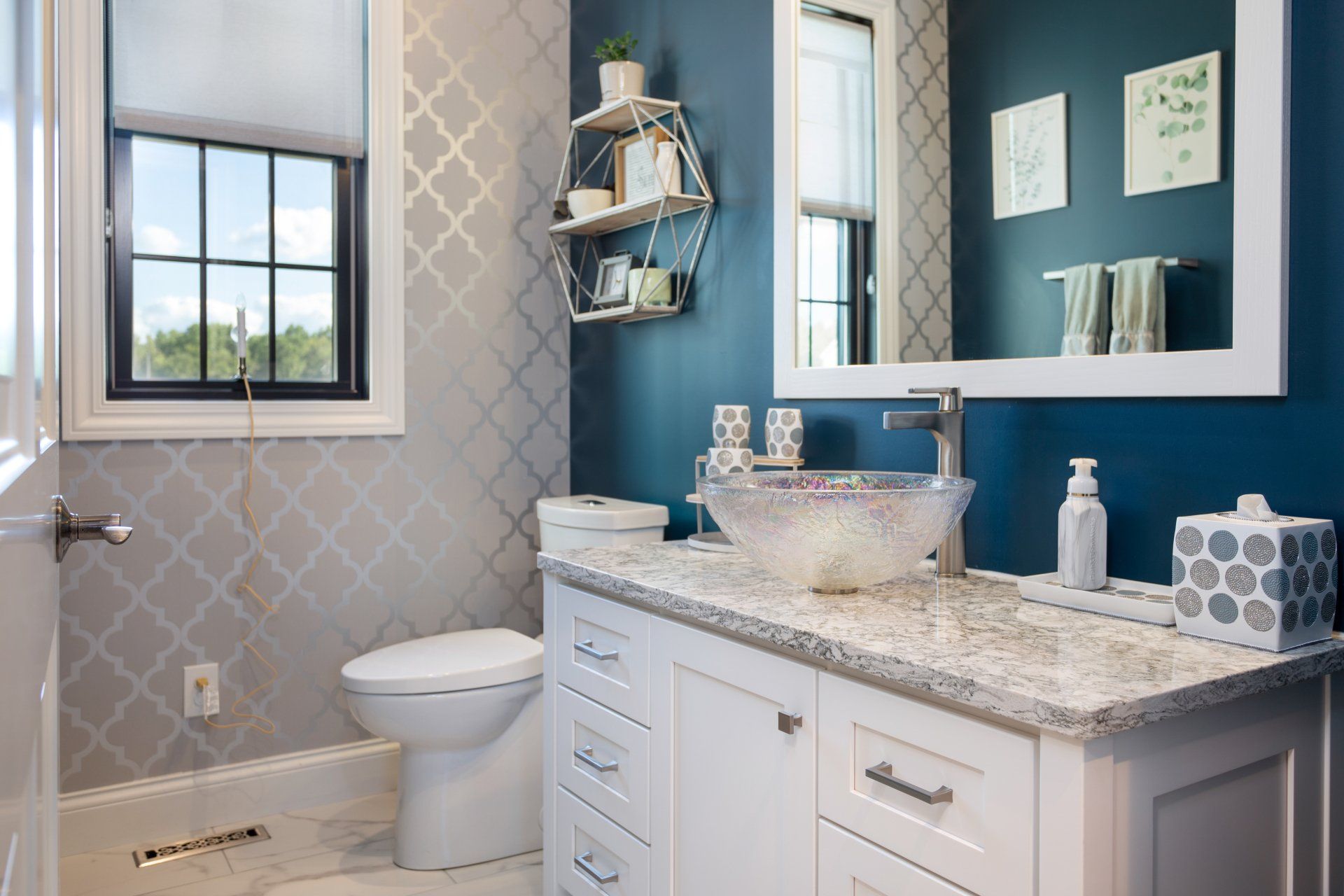 A bathroom with a toilet , sink , mirror and window.