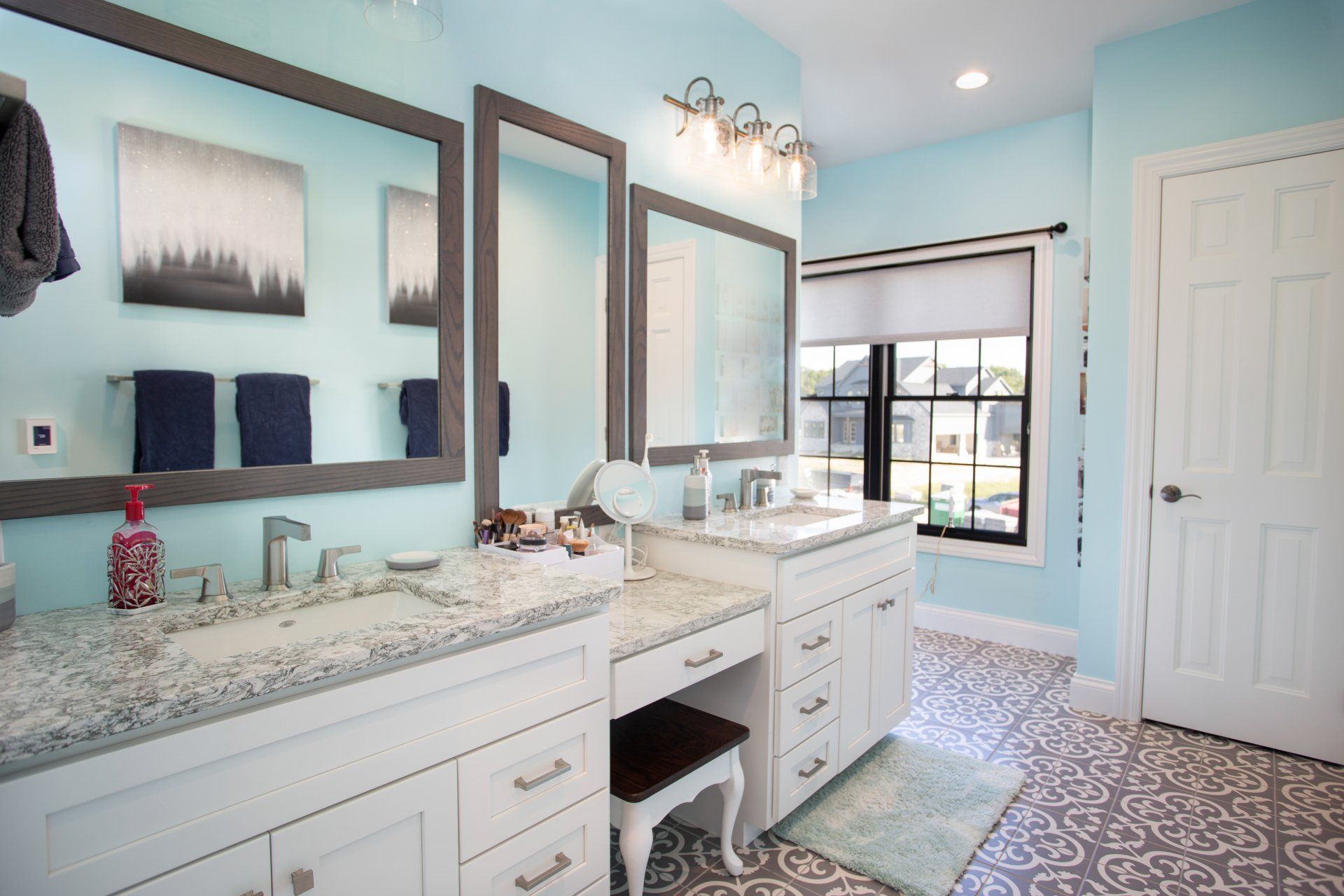 A bathroom with two sinks, two mirrors, and a window.