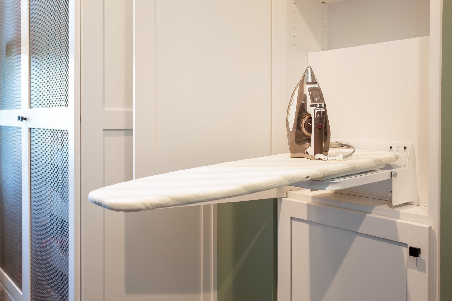 An iron is sitting on top of an ironing board in a closet.