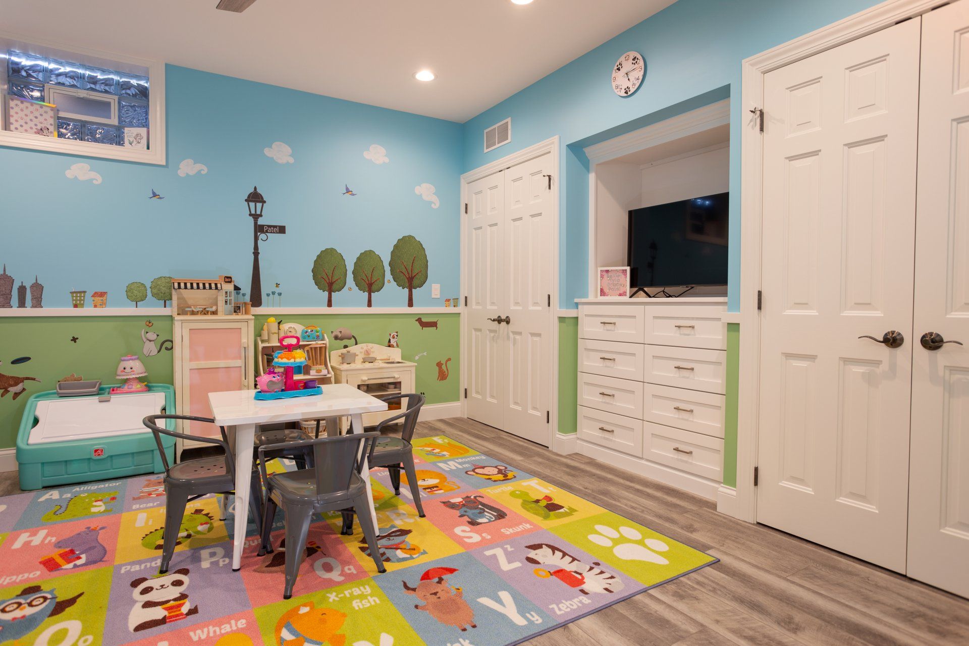 A play room with a table and chairs and a rug.