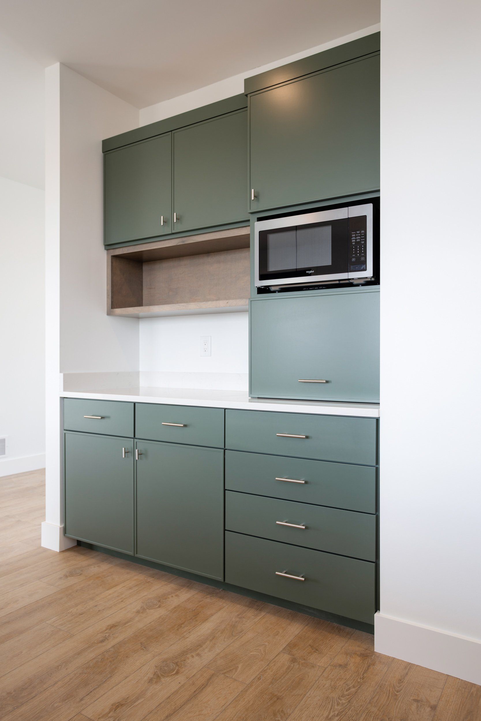 A kitchen with green cabinets and a microwave