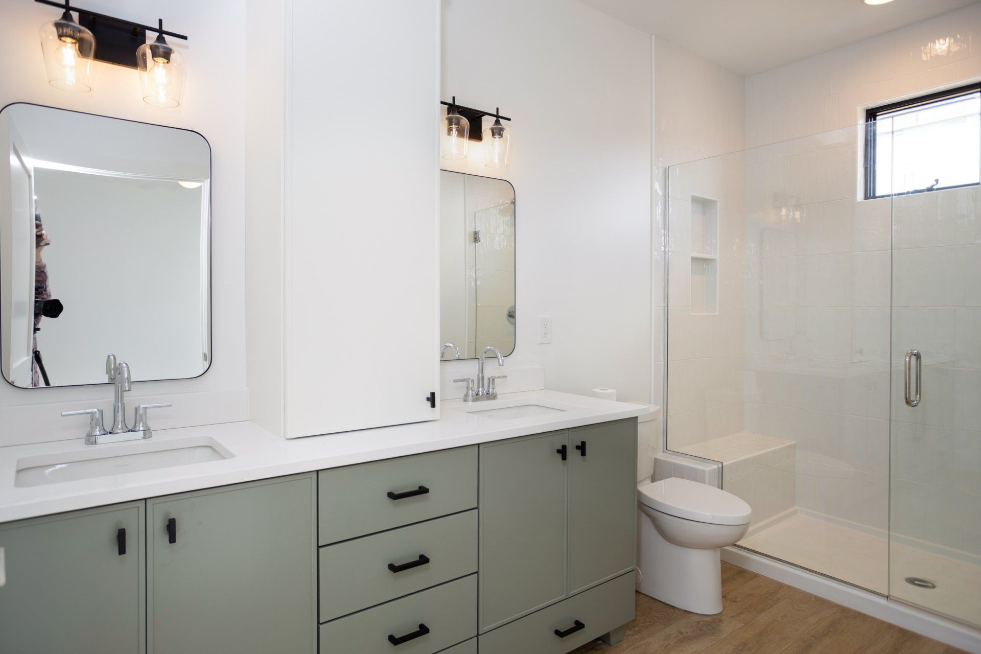 A bathroom with a toilet, sink, mirror and shower.