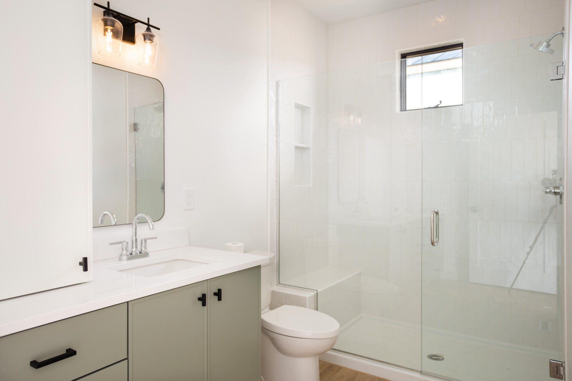 A bathroom with a toilet, sink, mirror and shower.