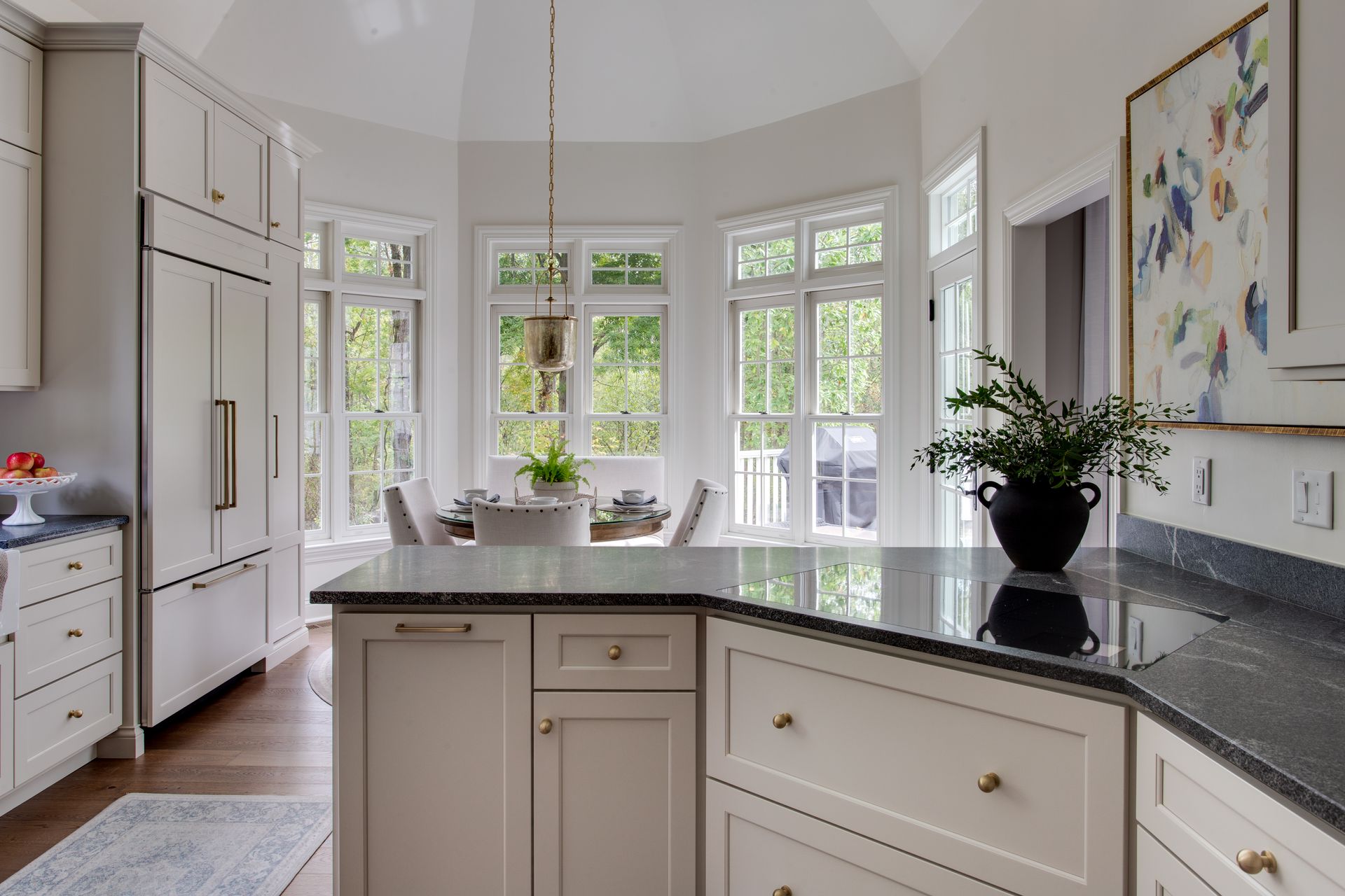 A kitchen with white cabinets , granite counter tops , and a large island.